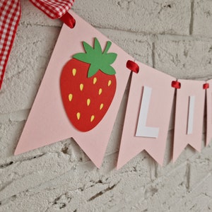 May include: Pink and white banner with the word "LIVE" in white letters and a red strawberry with green leaves.