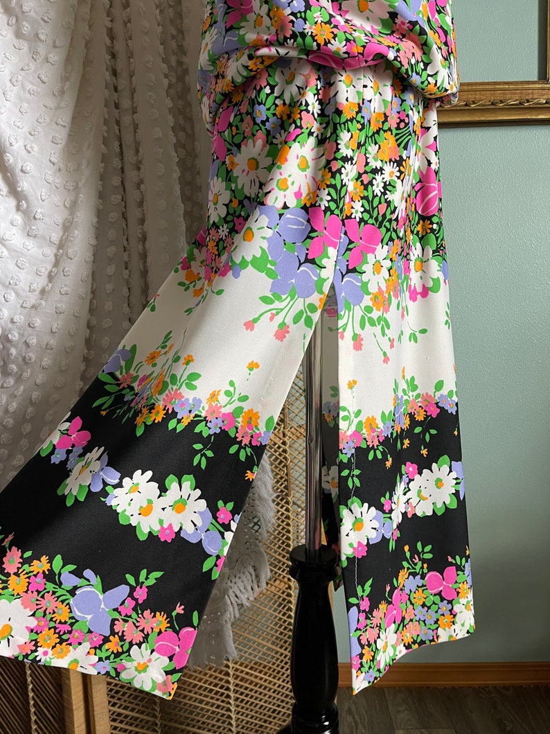 Puede incluir: Una falda de estampado floral blanco y negro con una abertura lateral. La falda tiene un fondo blanco con detalles florales negros y un fondo negro con detalles florales blancos.