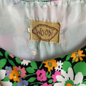Puede incluir: Un vestido de estampado floral blanco y negro con una etiqueta marr&oacute;n que dice "WOODI".