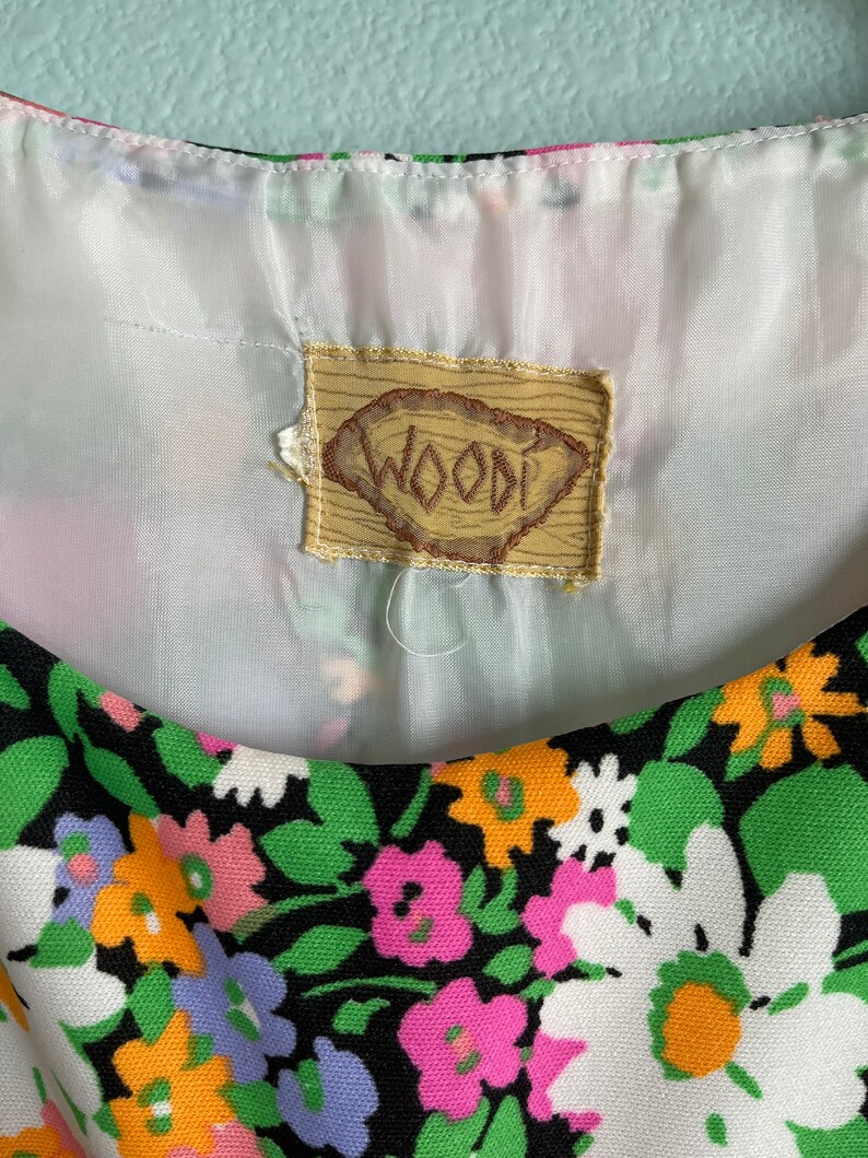 Puede incluir: Un vestido de estampado floral blanco y negro con una etiqueta marr&oacute;n que dice "WOODI".