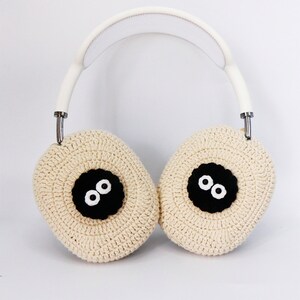 Pu&ograve; includere: Cuffie bianche con padiglioni auricolari in crochet beige che hanno occhi neri e un naso nero.
