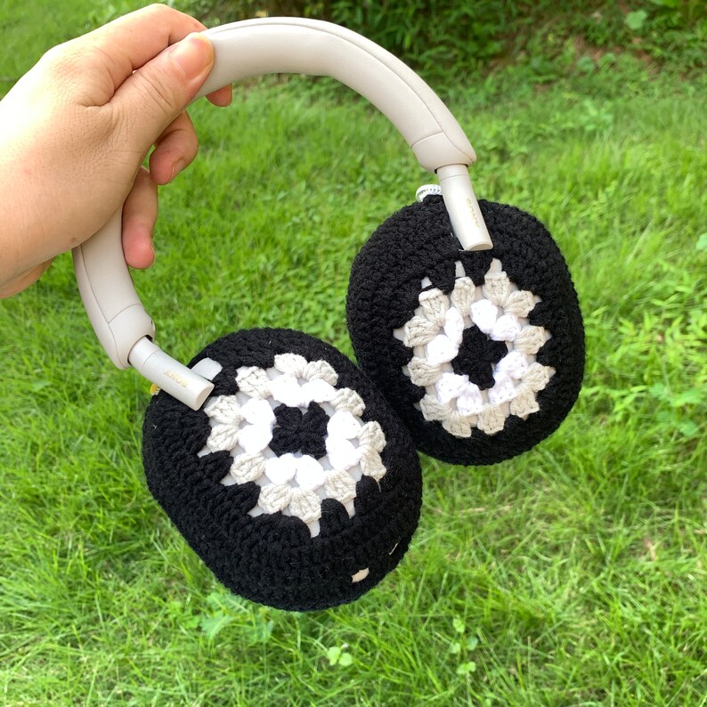 May include: White and black crocheted earmuffs with a gray headband. The earmuffs are made of a soft, textured yarn and are designed to cover the ears completely.