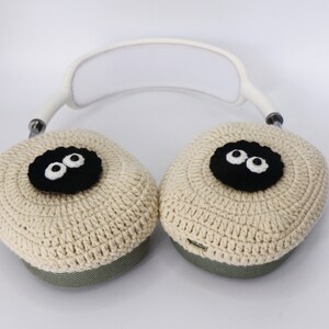 Pu&ograve; includere: Copri auricolari in crochet beige con occhi in feltro nero. Le cover sono attaccate a una fascia bianca.