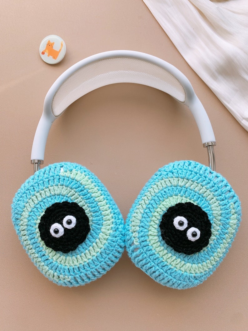 Pu&ograve; includere: Copri cuffie in crochet blu con occhi neri e fascia bianca.