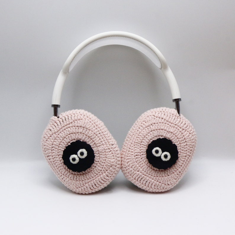 Pu&ograve; includere: Paraorecchie in crochet rosa con occhi in feltro nero. I paraorecchie sono attaccati a una fascia bianca.