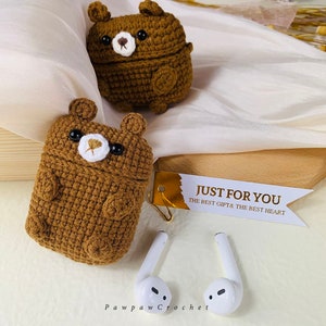 Puede incluir: Dos estuches para AirPod de color marr&oacute;n hechos a crochet con forma de oso, con ojos y narices blancas. Los estuches est&aacute;n sobre una superficie de tela blanca. El texto "Just for you, The best gift & the best heart" est&aacute; en una etiqueta blanca con detalles dorados.