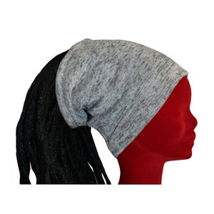 Peut inclure: Un bonnet gris avec une tresse noire attachée à l'arrière. Le bonnet est fait d'un matériau doux et extensible, idéal pour garder la tête au chaud en hiver.