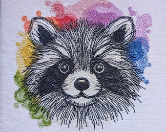 May include: Embroidered design of a raccoon's face with a colorful watercolor background. The raccoon has black fur, a white nose, and black eyes.