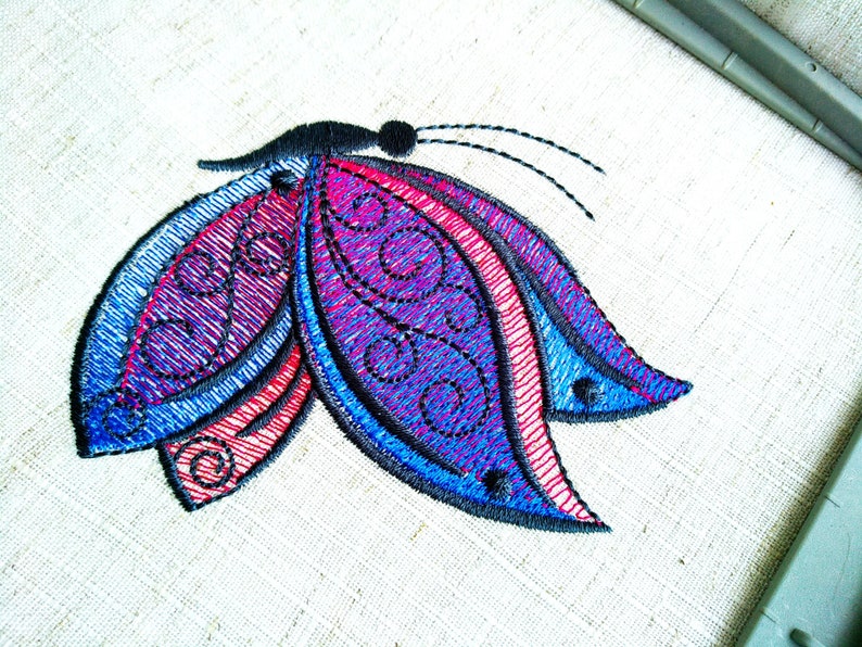 May include: Embroidered butterfly design with blue, purple, and red colors. The butterfly has intricate details and a black outline.