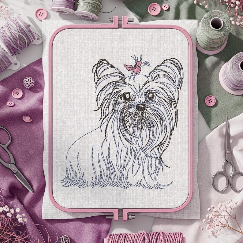 K&ouml;nnte beinhalten: Ein rosa Stickrahmen zeigt ein detailliertes Stickbild eines Yorkshire Terrier-Hundes. Der Hund ist mit schwarzem und blauem Garn gestickt, mit einer rosa Schleife. N&auml;hzubeh&ouml;r, einschlie&szlig;lich Garnrollen, Scheren und Kn&ouml;pfen, umgibt den Rahmen.