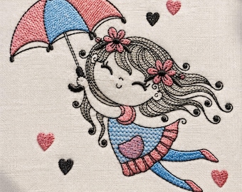 May include: An embroidery hoop containing a fabric panel with a stitched illustration of a character holding a pink and blue umbrella. The character has long dark hair with pink flowers, a blue dress, and blue leggings, surrounded by small pink and black hearts.