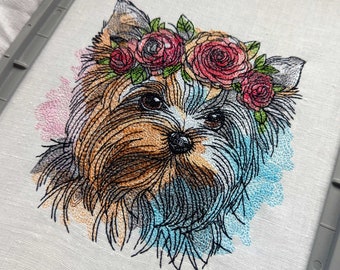 May include: Embroidered image of a Yorkshire Terrier wearing a flower crown. The dog is brown and white with a black nose and has a watercolor background.