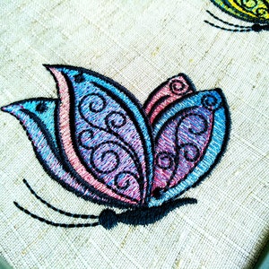 May include: Embroidered butterfly design with blue, pink, and purple colors on a beige fabric background.