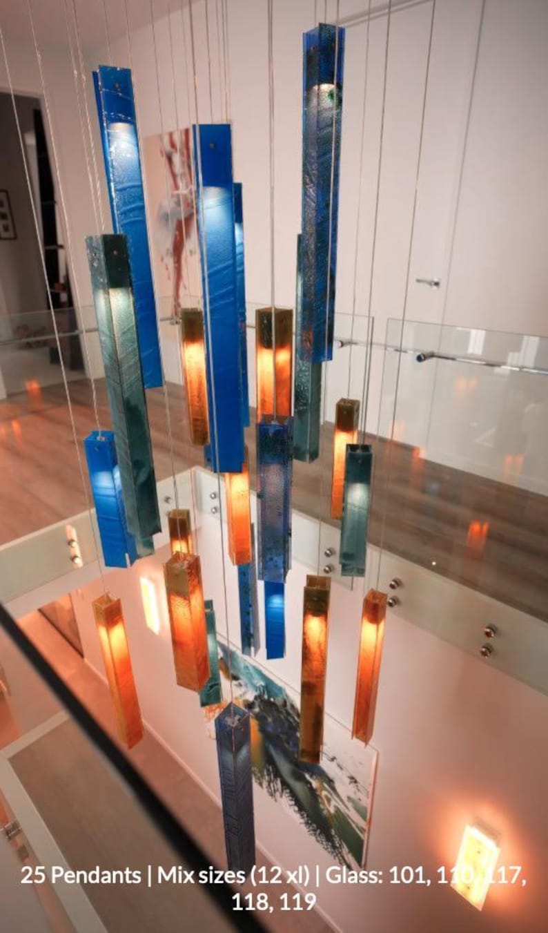 a modern and stylish interior design with a striking chandelier made of colorful glass rods suspended from the ceiling. The chandelier has a mix of blue, orange, and green glass rods, creating a visually appealing and vibrant display. The overall design and arrangement of the chandelier contribute to the contemporary and sophisticated atmosphere of the space.