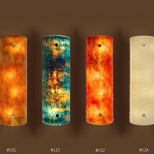 a group of four different colored vases sitting next to each other