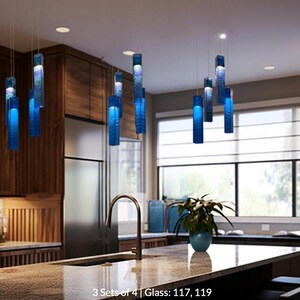 a modern kitchen with a large island, a sink, and a variety of blue pendant lights hanging above it. The kitchen has wooden cabinets and a large window that provides natural light.