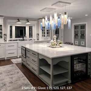 A modern and spacious kitchen with white cabinets, a large central island, and a hanging light fixture.