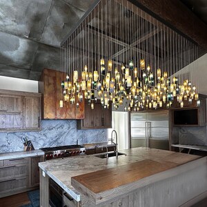 a modern kitchen with a large, intricate chandelier made of numerous small glass bottles suspended from the ceiling, creating a striking and visually appealing lighting fixture.