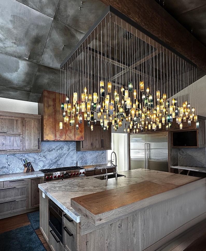 a modern kitchen with a large, intricate chandelier made of numerous small glass bottles suspended from the ceiling, creating a striking and visually appealing lighting fixture.