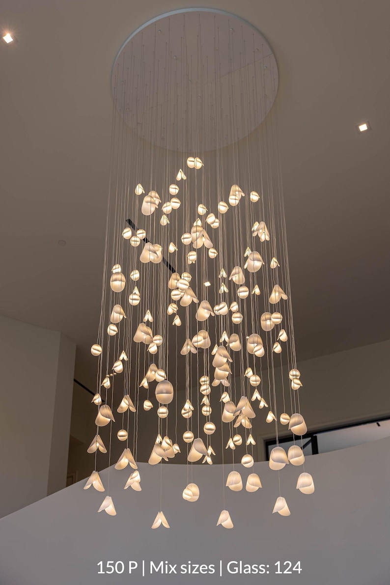 a large, intricate chandelier with numerous small, white lights suspended from the ceiling. The chandelier has a circular base and is composed of numerous hanging light fixtures, creating a visually striking and elegant display.
