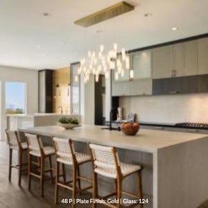 a modern kitchen with a large island, wooden barstools, and a hanging light fixture above the island.