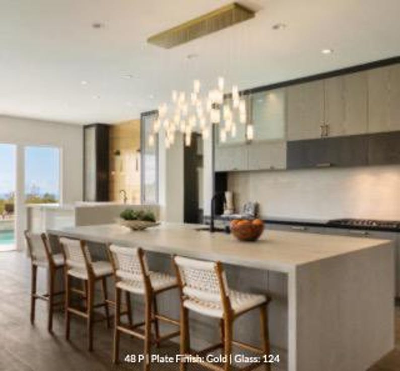 a modern kitchen with a large island, wooden barstools, and a hanging light fixture above the island.