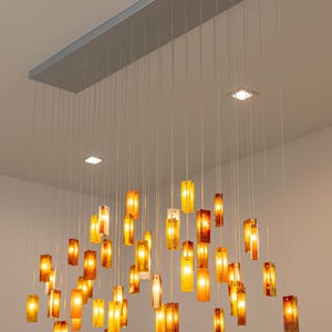 a modern, hanging light fixture with numerous small, rectangular light bulbs suspended from the ceiling. The light bulbs are arranged in a grid-like pattern, creating a visually striking and contemporary design.