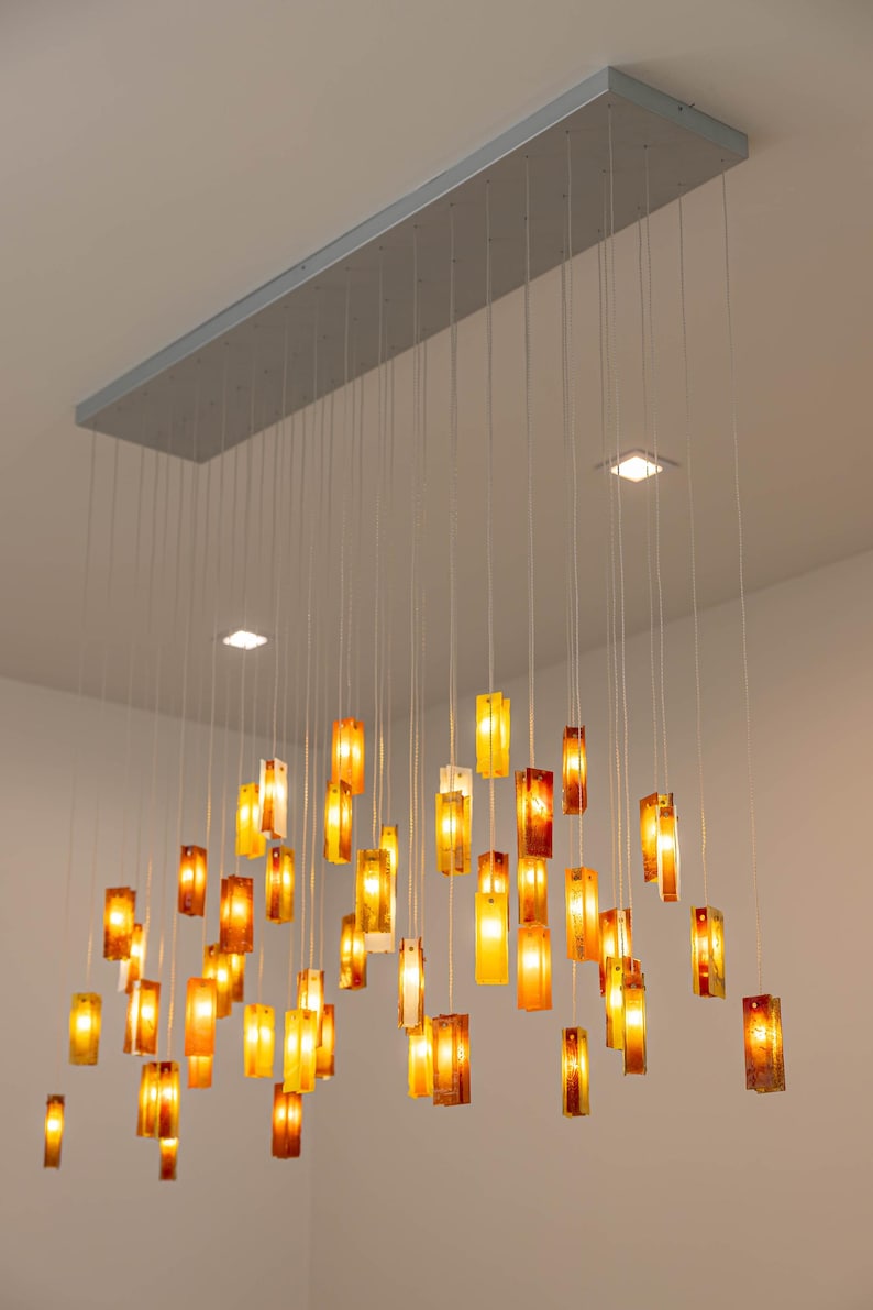 a modern, hanging light fixture with numerous small, rectangular light bulbs suspended from the ceiling. The light bulbs are arranged in a grid-like pattern, creating a visually striking and contemporary design.