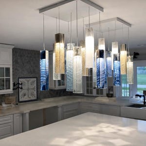 a modern kitchen with a large, stylish pendant light hanging from the ceiling. The light has a mix of blue and white glass elements, creating a visually appealing and contemporary design. The kitchen is well-equipped with white cabinets and a large island countertop, providing ample space for cooking and dining.