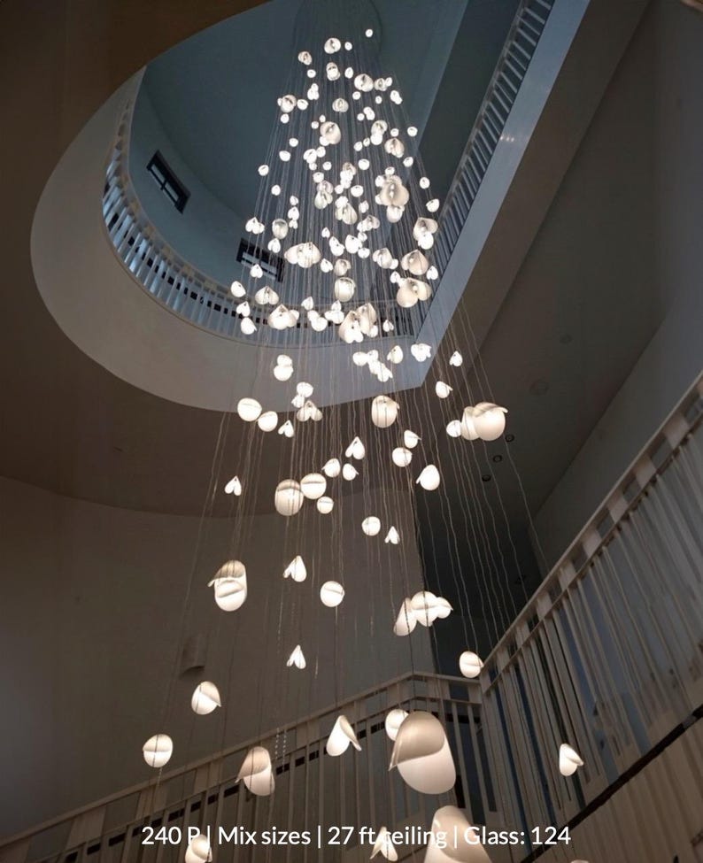 a large, intricate chandelier hanging from the ceiling of a building, composed of numerous small white lights suspended from strings.