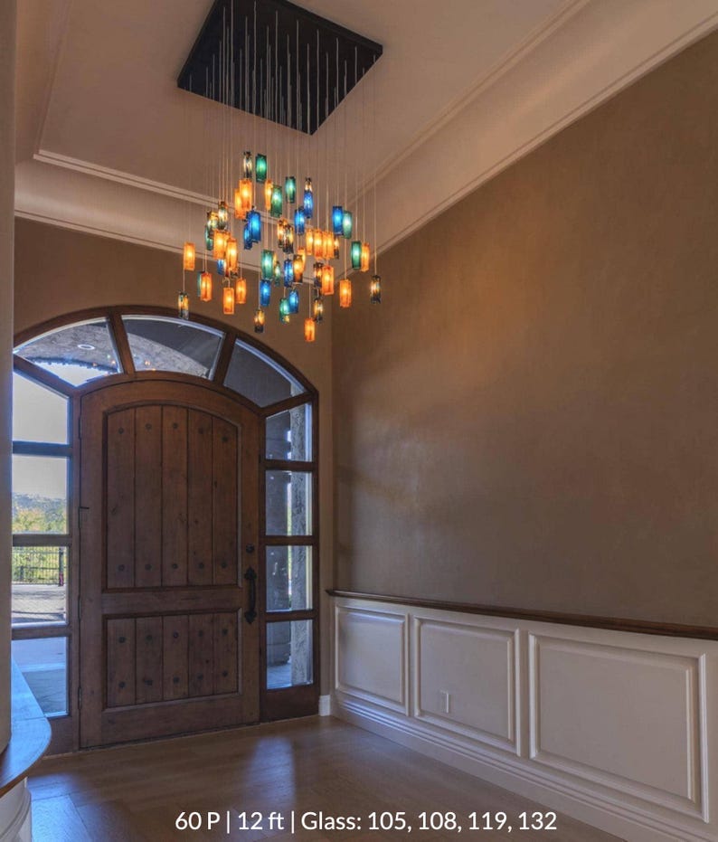 a large wooden door with a glass panel, and above it is a chandelier with colorful glass shades. The room has a beige wall and a wooden floor.