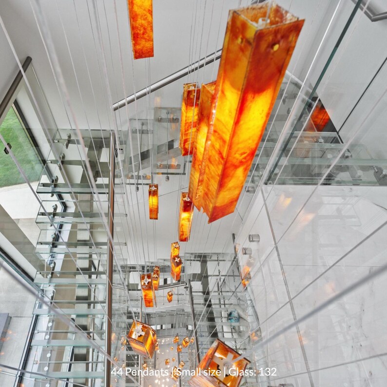 a modern, glass-walled interior space with a striking arrangement of orange pendant lights suspended from the ceiling.