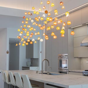 a modern kitchen with a large, hanging light fixture composed of numerous glass spheres in various colors, creating a visually striking and vibrant atmosphere.
