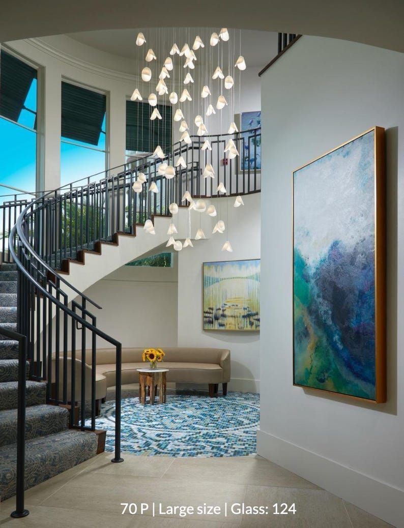 A modern and stylish interior with a large staircase, a hanging chandelier, and artwork on the walls.