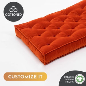 Puede incluir: Un cojín rectangular naranja con un diseño acolchado. El cojín está hecho de una tela suave y tiene un borde cosido. El texto "CUSTOMIZE IT" se muestra en la parte inferior de la imagen.
