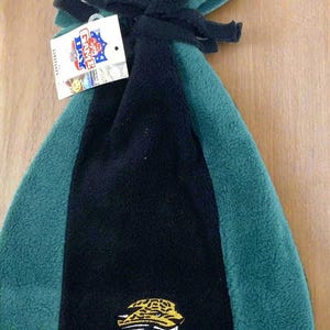 May include: A black, teal, and green fleece beanie with the Jacksonville Jaguars logo. The hat has a tag that says "Game Day". The beanie is made of soft fleece material and has a knotted top.