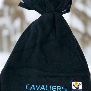 May include: Black fleece hat with a knotted top. The word "CAVALIERS" is embroidered in blue, along with a team logo. This winter hat is perfect for fans of the Cleveland Cavaliers basketball team.