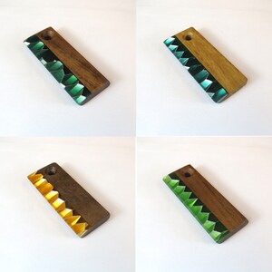 May include: Four wooden keychains with a green and gold resin inlay. The keychains are rectangular and have a hole at the top for attaching to a key ring.