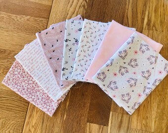 May include: A set of six fabric squares with different floral patterns in shades of pink and white. The fabrics feature delicate floral designs, including small flowers, leaves, and hearts.