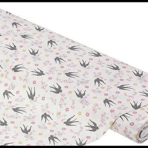 May include: White fabric with a repeating pattern of small pink flowers and black silhouettes of birds. The fabric is rolled up and the end is visible.