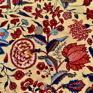 Puede incluir: Una tela de color crema con un patrón floral repetitivo. Las flores son rojas, azules y amarillas. La tela tiene un aspecto vintage.