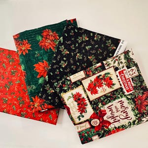 Peut inclure: Quatre pièces de tissu pliées sur le thème de Noël avec des poinsettias rouges, des feuilles de houx vertes et des baies. Un morceau présente des cartes de style vintage avec le texte Merry and bright, Seasons greetings et A Merry Christmas.