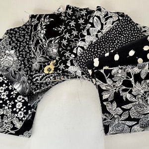 May include: A collection of black and white fabric squares with various floral and geometric patterns. The fabric squares are arranged in a semi-circle.