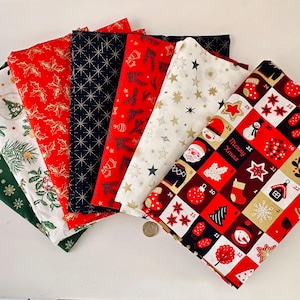 Peut inclure: Un ensemble de sept carrés de tissu pliés présentant divers motifs sur le thème de Noël, notamment du houx, des étoiles, des branches de pin et une grille de calendrier de l'Avent numérotée avec le texte Merry Xmas en rouge, vert, blanc, noir et or.