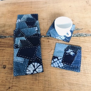 May include: Set of six blue and white patchwork fabric coasters. The coasters are made from repurposed denim and have a variety of patterns and textures.