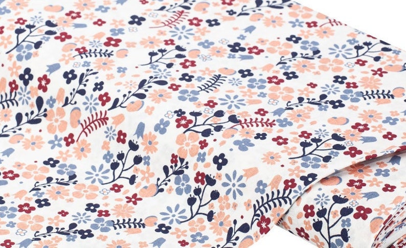 May include: White fabric with a repeating pattern of small pink, red, and blue flowers and leaves.