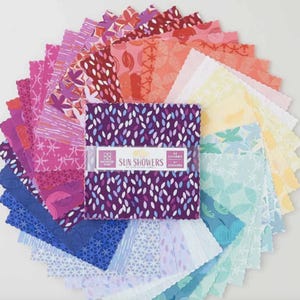 Peut inclure: Un ensemble de 42 carrés de tissu aux couleurs et motifs variés, disposés en éventail circulaire. Les carrés présentent des teintes roses, violettes, oranges et bleues, avec des motifs floraux et abstraits. L'emballage central porte l'inscription "Sun Showers".