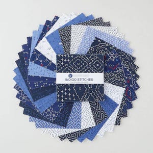 May include: A stack of square fabric swatches arranged in a circular fan pattern. The fabric features various shades of blue and white with geometric, floral, and dashed patterns. A paper band reads INDIGO STITCHES by Whistler Studios.