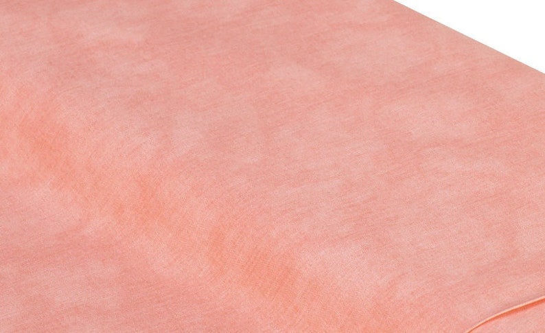 May include: A close-up of a smooth, peach-colored fabric with a subtle texture. The fabric is soft and has a slightly iridescent sheen.