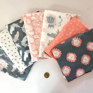 Peut inclure: Un assortiment de carrés de tissu à motifs dans diverses couleurs, dont le gris, le blanc et le corail. Les tissus présentent des motifs animaliers et géométriques, tels que des lions, des crocodiles et des triangles. Une pièce d'or est visible.